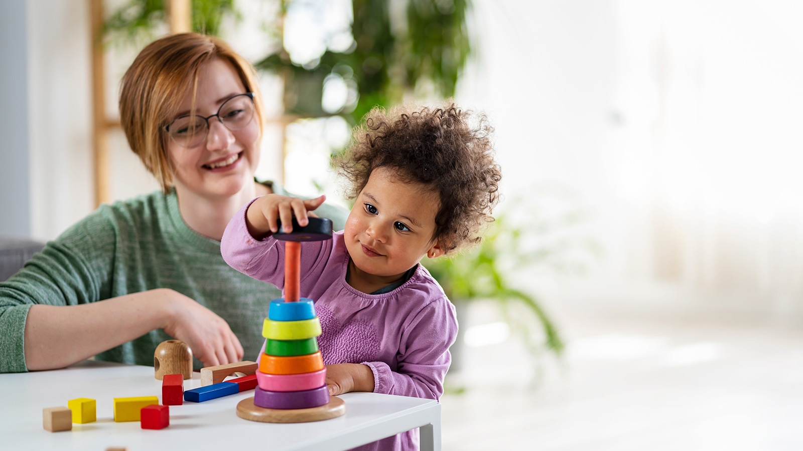 Teacher looking at a child playing with an educational didactic toy