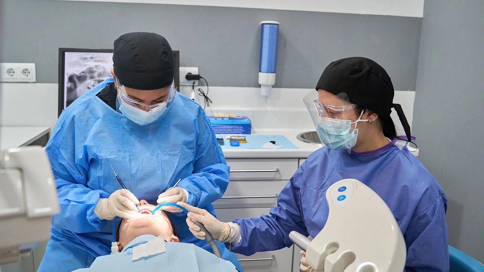Student assisting dentist with a teeth cleaning