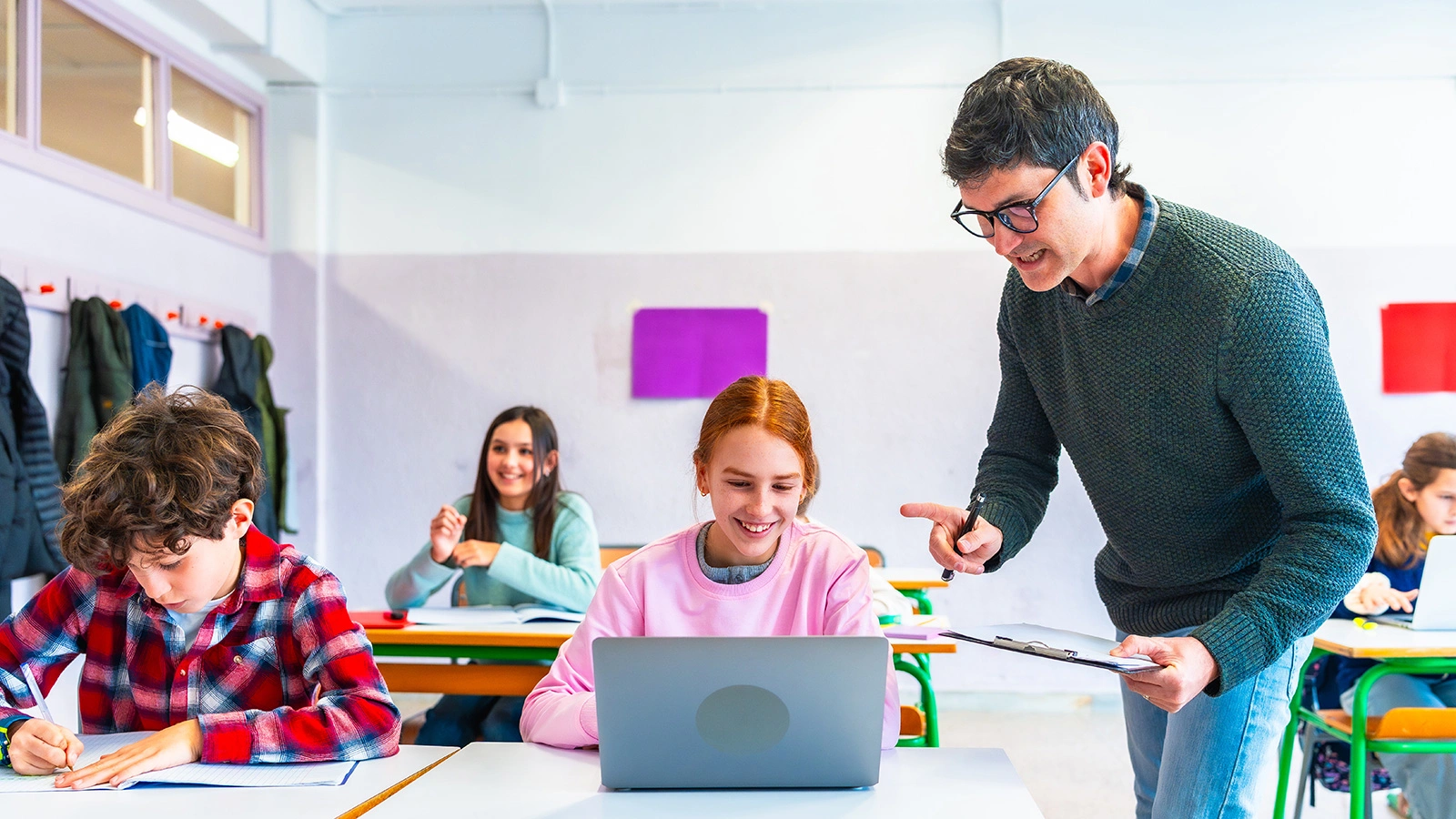 Teacher helping students studying with laptop