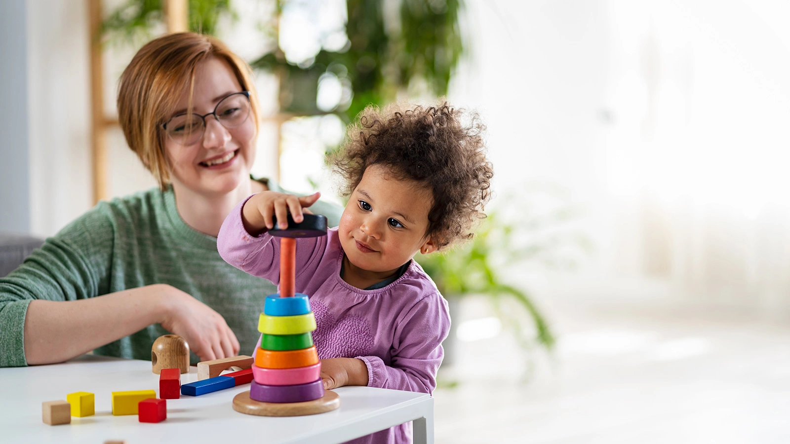 Teacher looking at a child playing with an educational didactic toy
