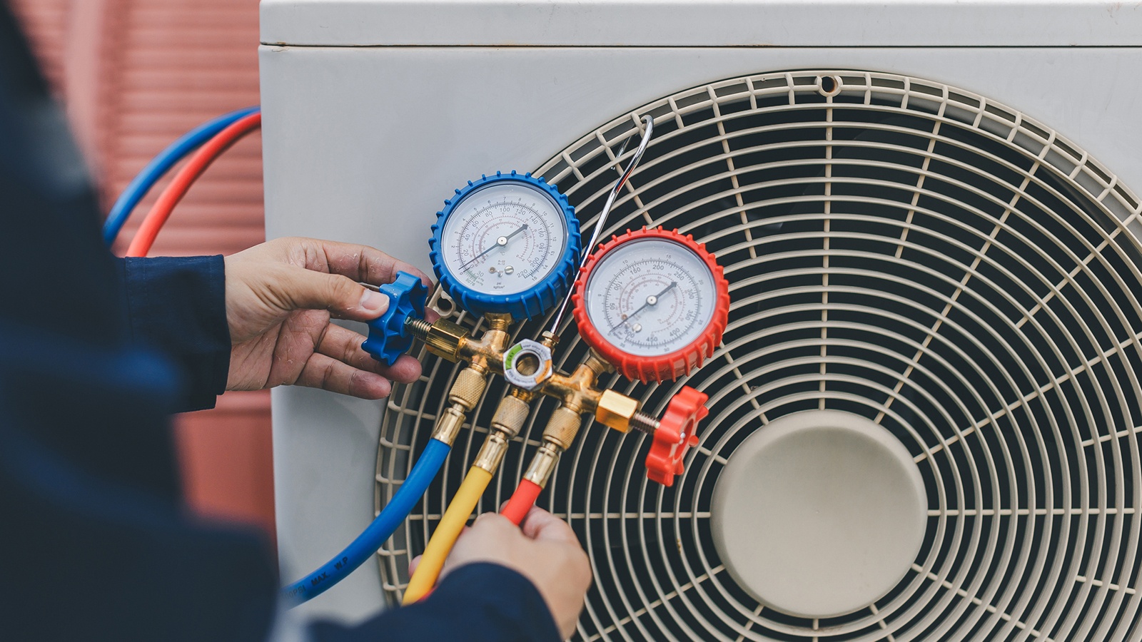 HVAC Technician reading a gauge from an ac compressor