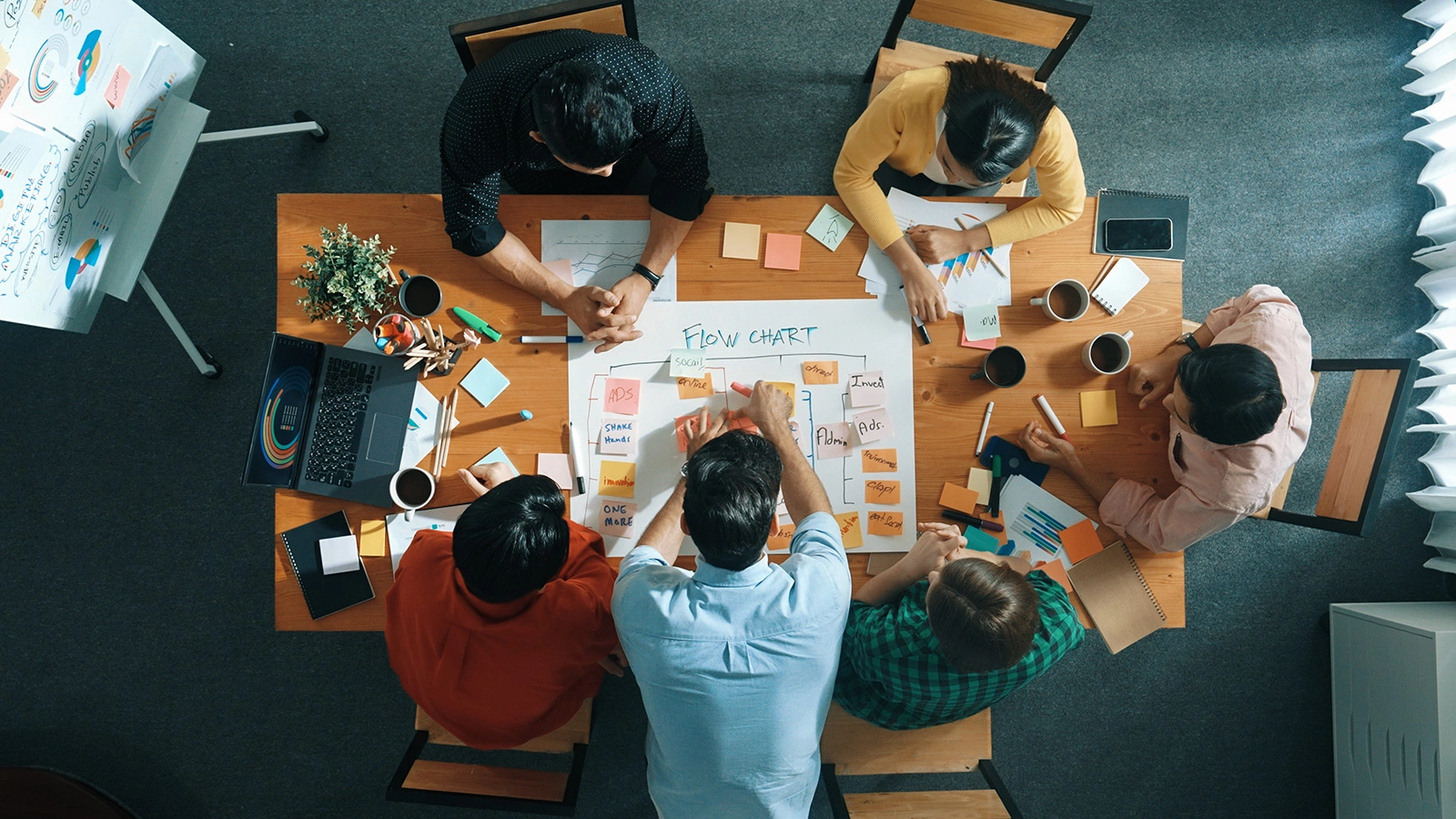 A group of people putting scrum board on table at meeting room.