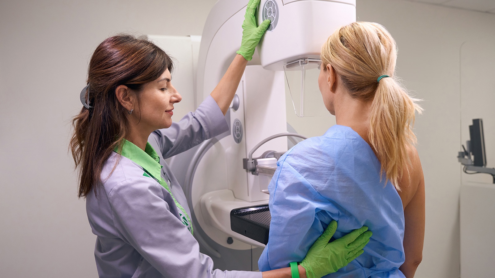 Professional radiographer preparing client for diagnostic mammogram