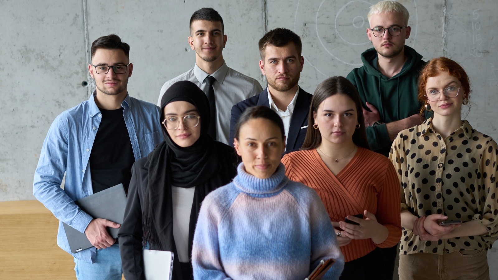 A diverse group of eight students look forward and pose.
