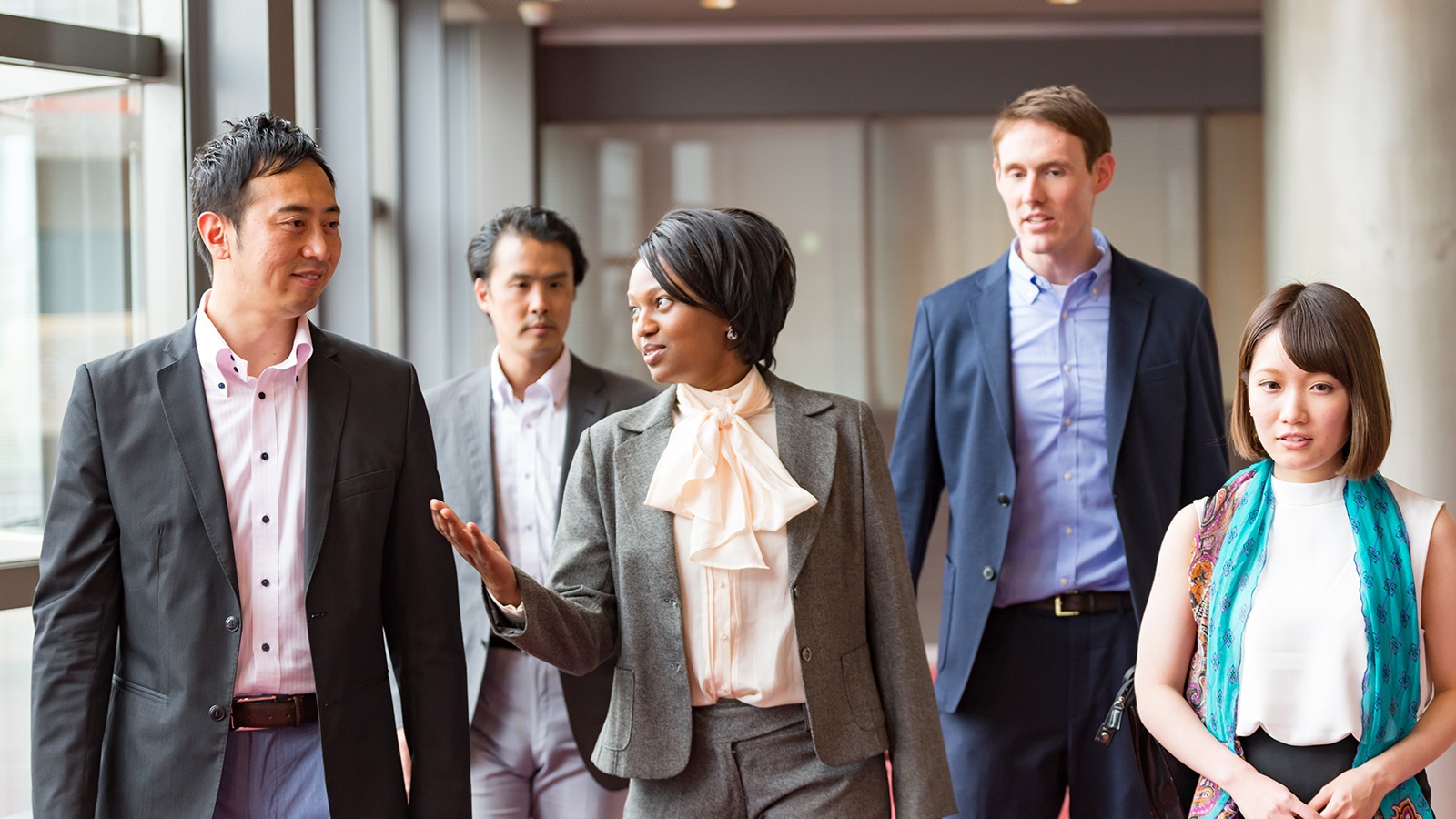 International businesspeople are walking together at hallway of office building