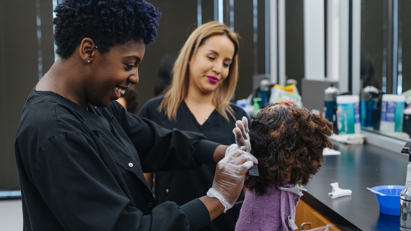 Instructor watching student do client hair.