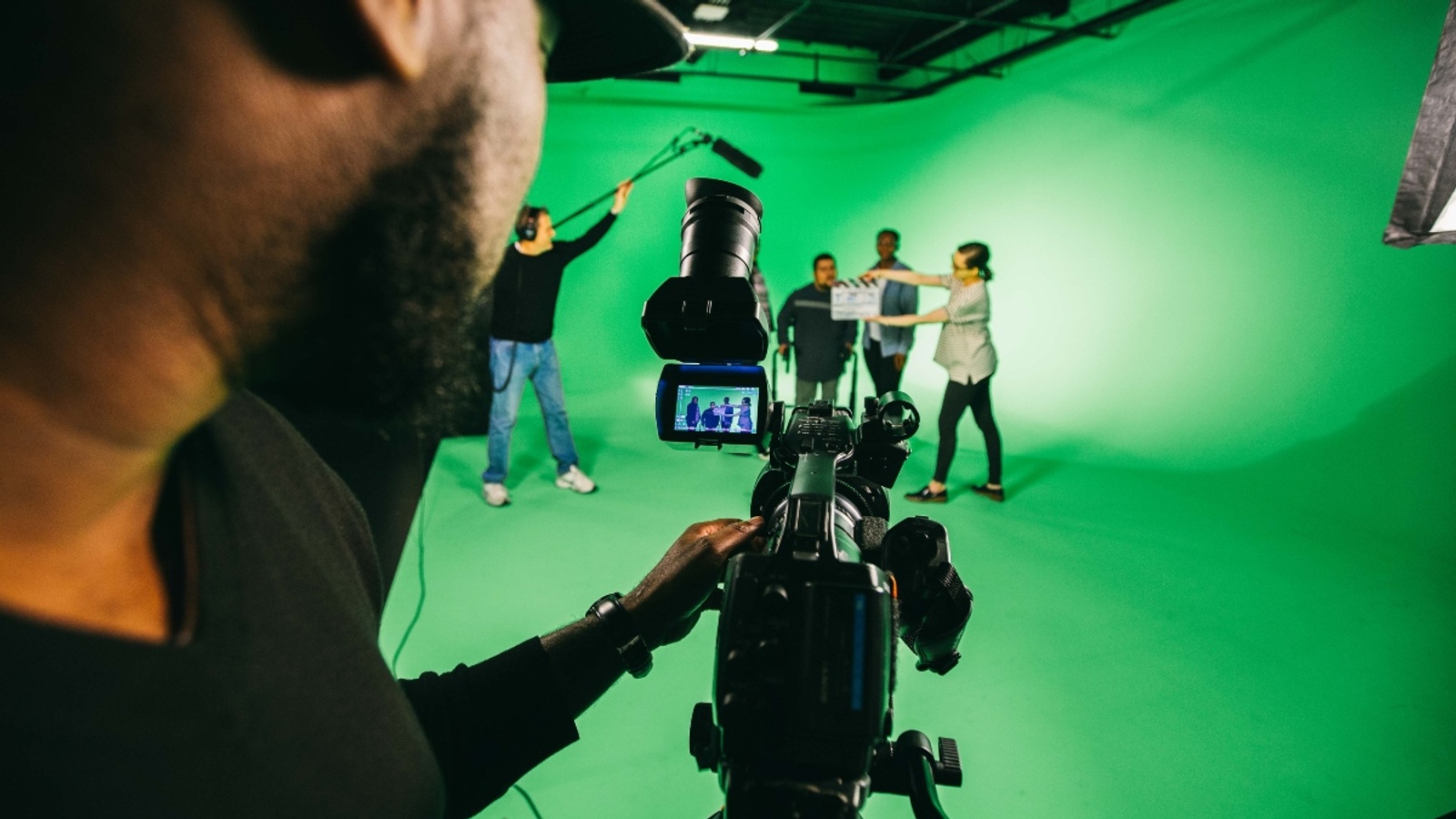 A filmmaking student behind a camera filming a scene on set