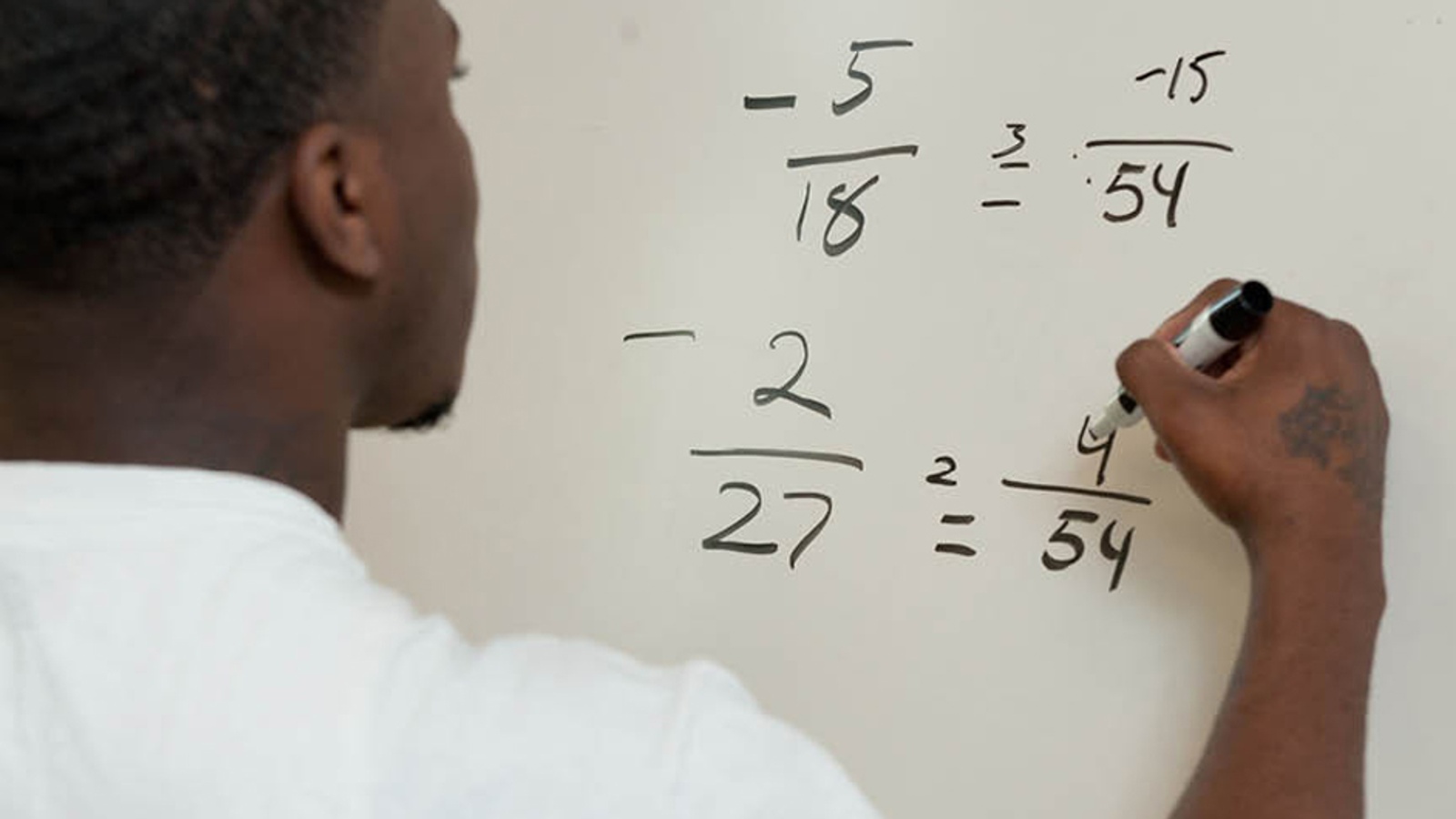 Student solving an equation on a white board