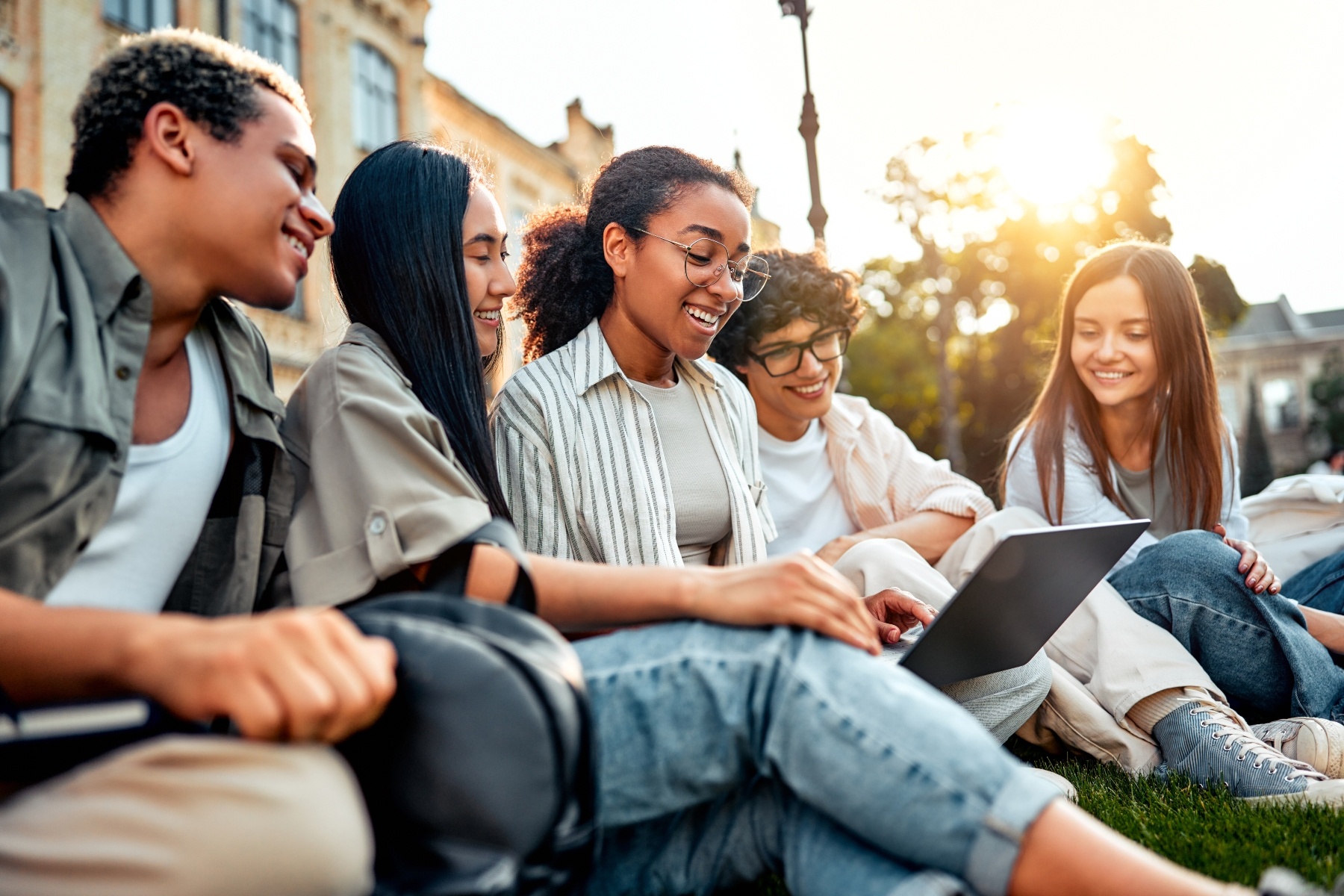 Students gather around a laptop computer.