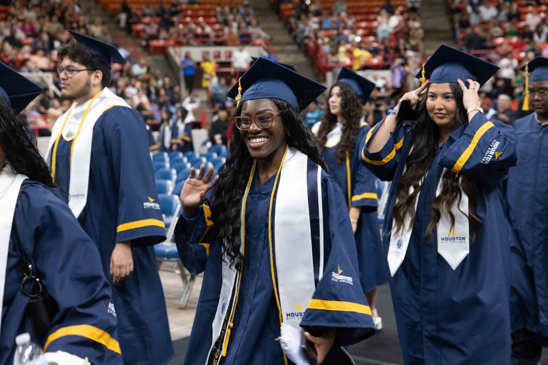 An HCC graduate waves while walking at the Commencement Ceremony.