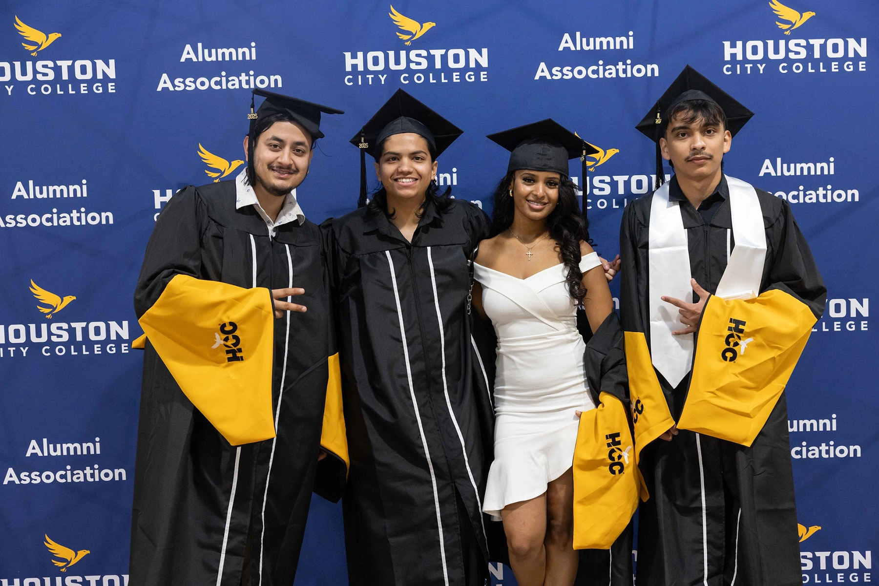 HCC Graduates in front of the Alumni Association backdrop