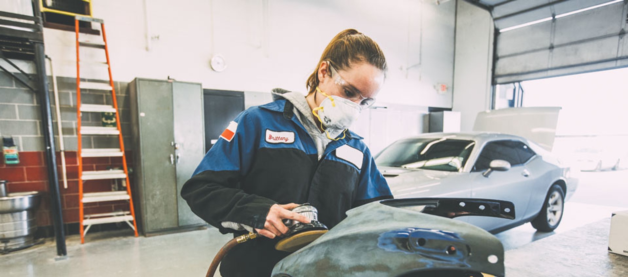 Automotive repair student fixing a car fender