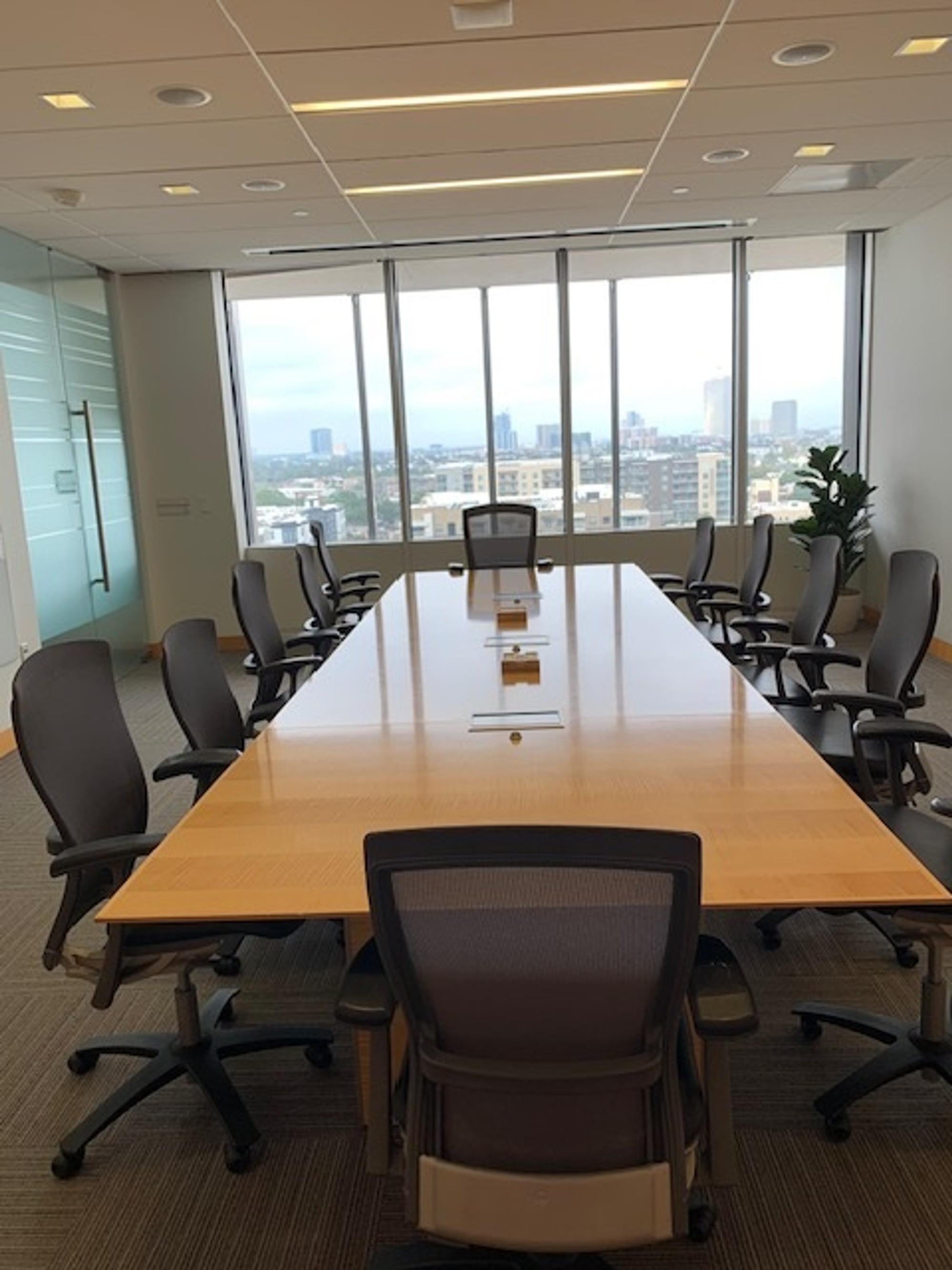 Photo of the meeting space layout for the Atlantic Room featuring a long table and chairs infront of a panaromic window view of the city