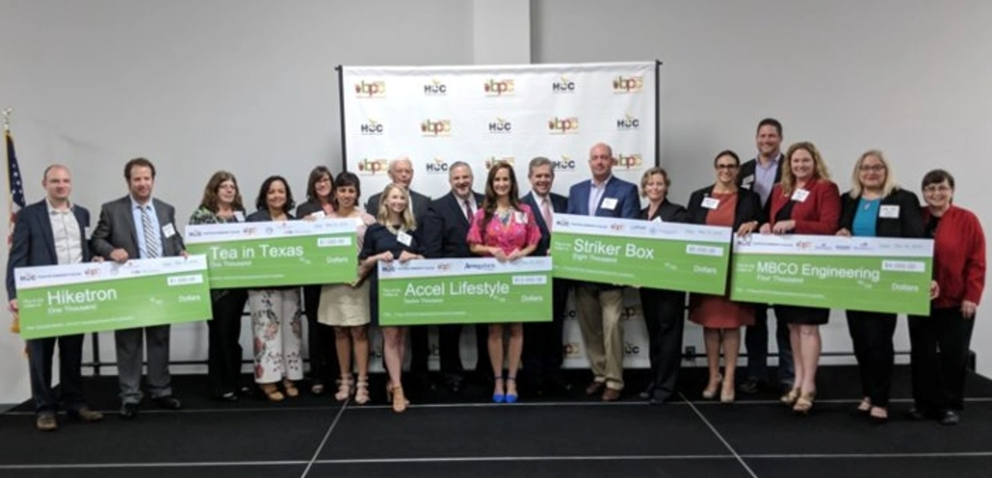 The 2018 Business Plan Competition winners hold large checks as they pose for a group photo during a ceremony.