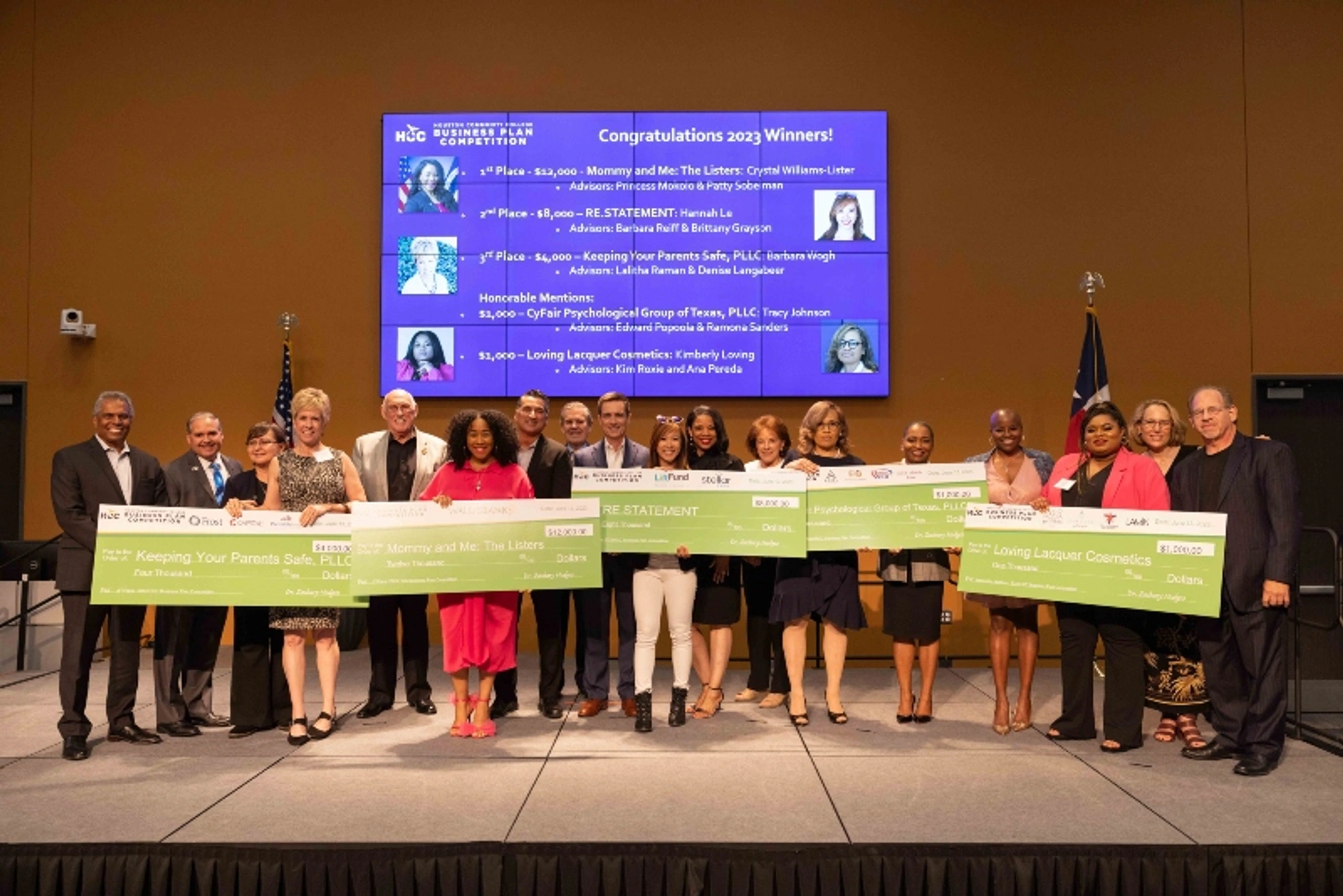 The 2023 Business Plan Competition winners hold large checks as they pose for a group photo during a ceremony.