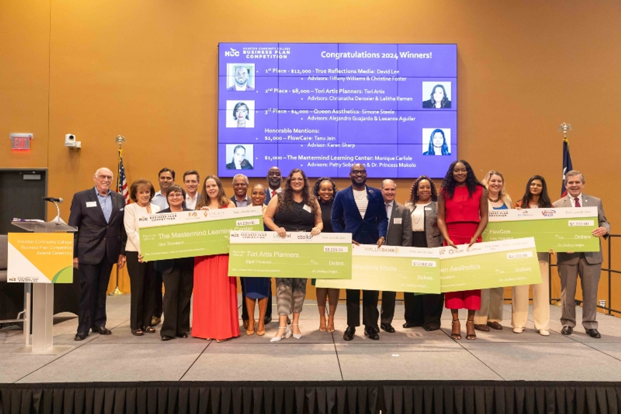 The 2024 Business Plan Competition winners hold large checks as they pose for a group photo during a ceremony.