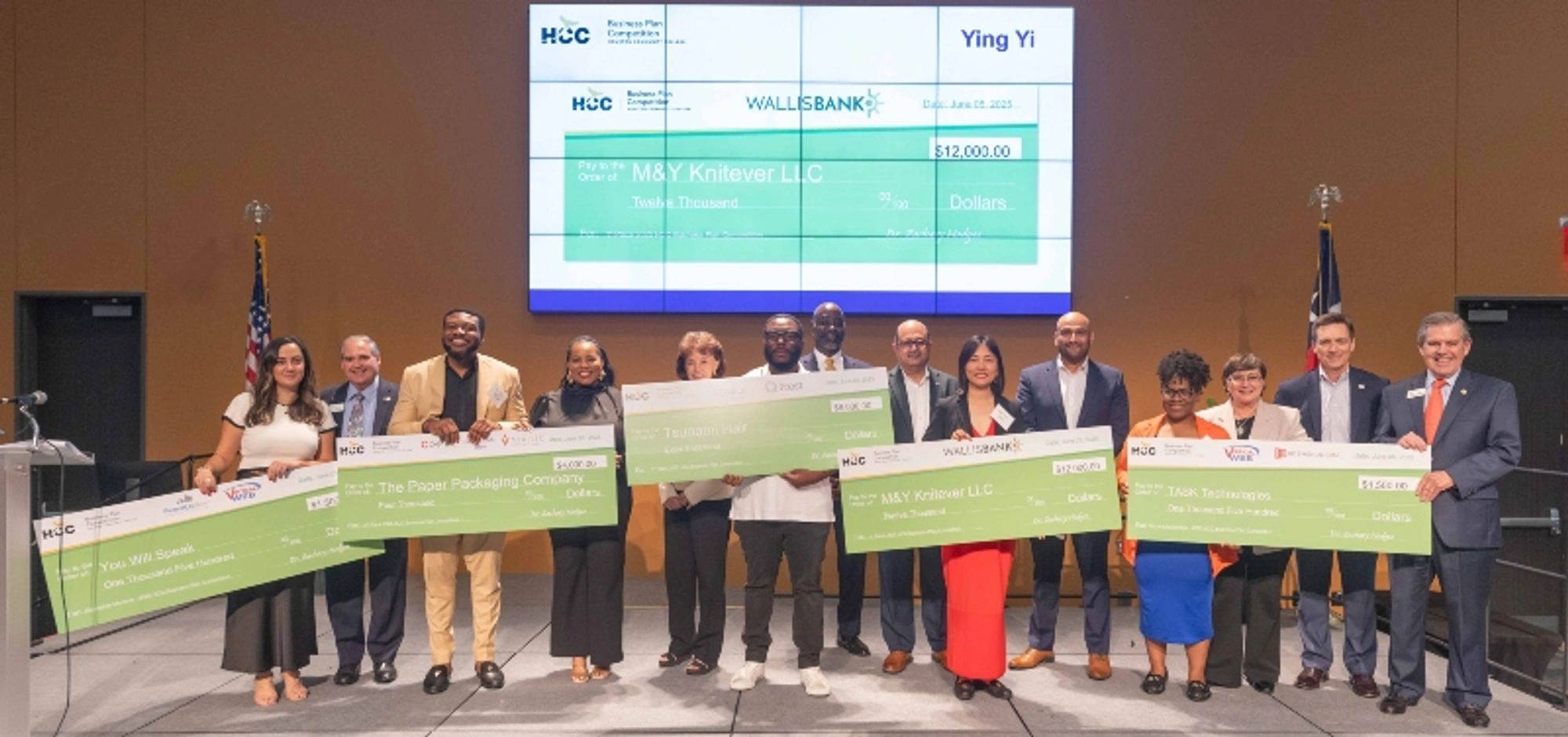 The 2025 Business Plan Competition winners hold large checks as they pose for a group photo during a ceremony.