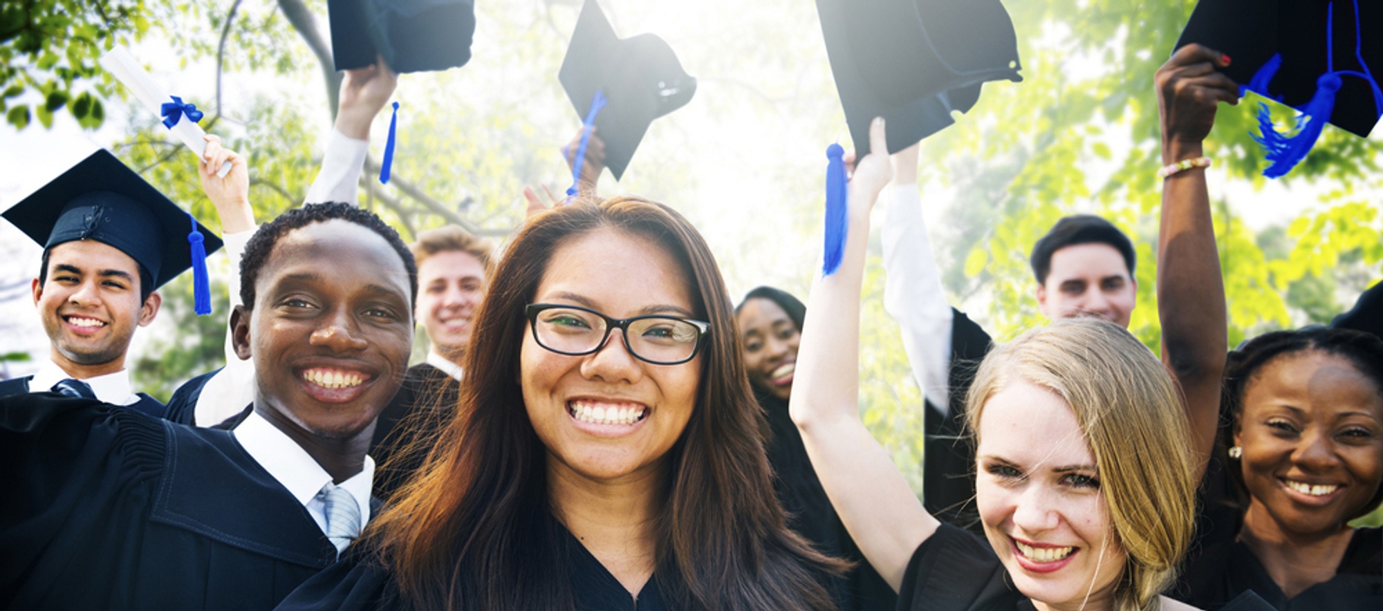 A diverse group of graduates remove their grad caps.