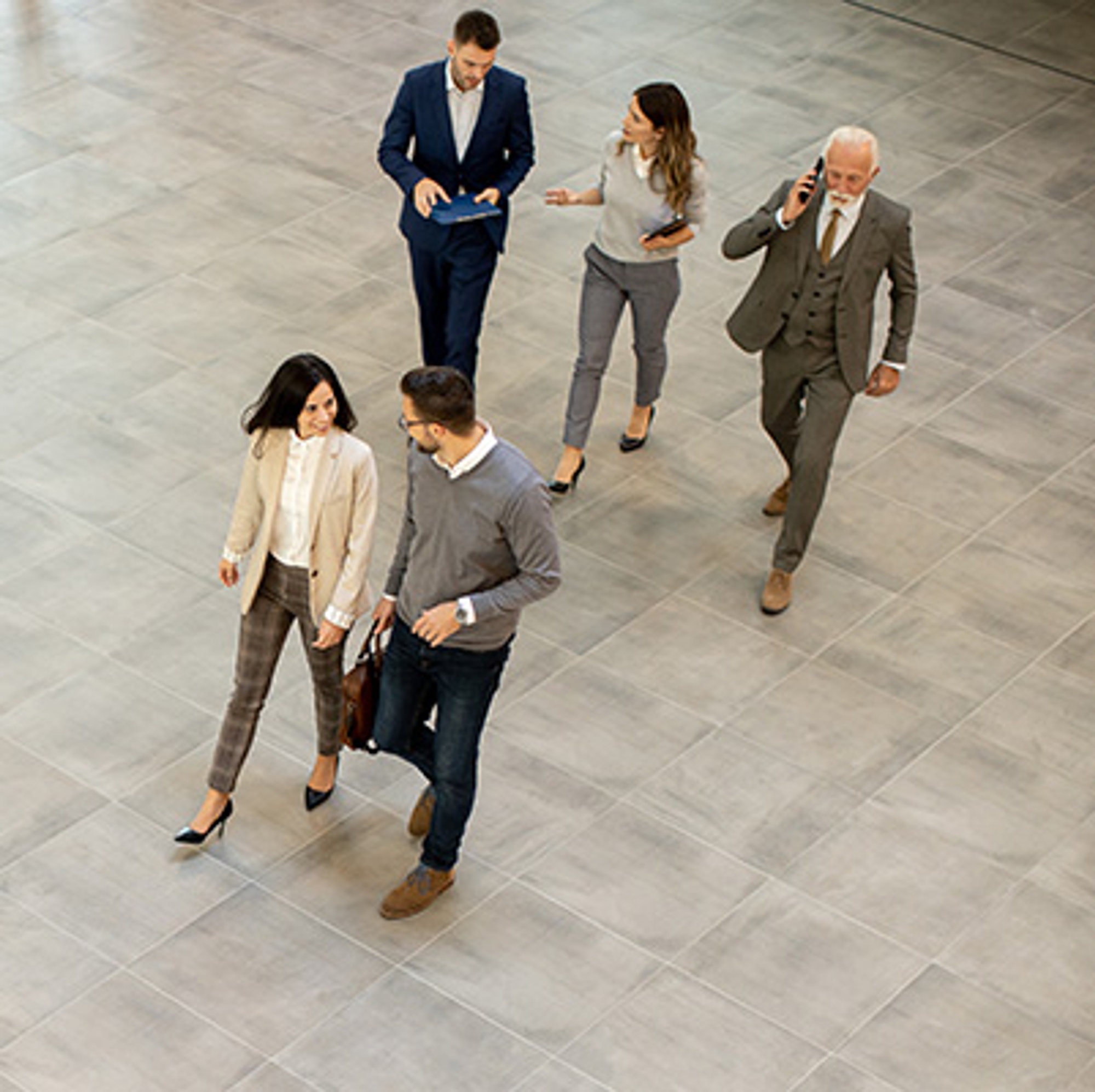 A group of five employees walking in an office lobby