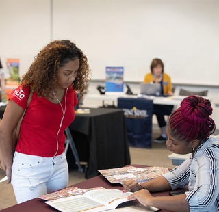 Student visiting transfer school tables at a transfer fair