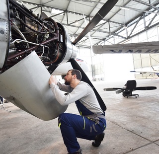 Airplane mechanic checking the engine of a plane
