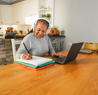 A woman taking classes on her laptop in her dining room