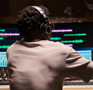 Audio engineer editing music at a mixing console