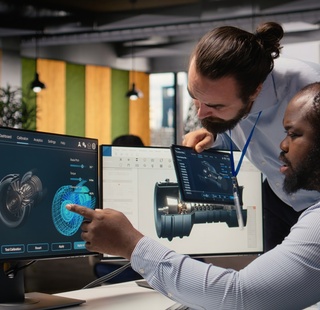 Two engineers look at turbine selectors on a computer screen.