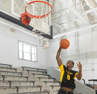 A student shoots a layup in the basketball gym.
