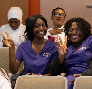 HCC Coleman College for Health Sciences students smile and wave as they pose for a photo.