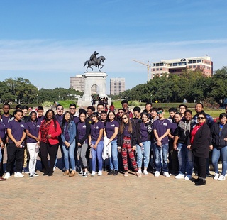 Upward Bound students in front of the Hermann Park statue during a class trip