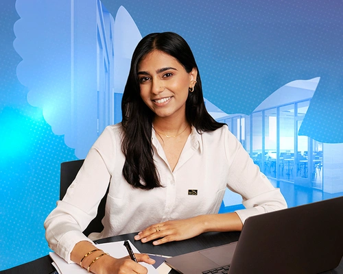 Female student writing notes while using her laptop