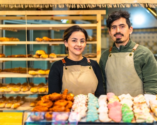 Small business owners posing infront of their bakery