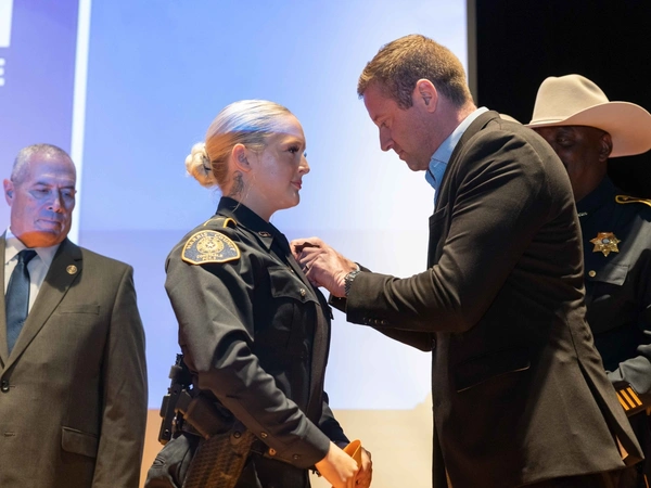 An HCC cadet receives her badge from a law enforcement agency.