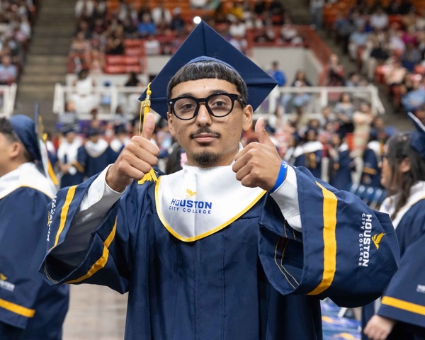 An HCC graduate gives the double thumbs up sign during the Commencement Ceremony.