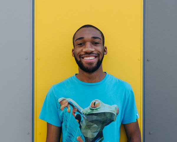 Male student standing in front of a yellow wall
