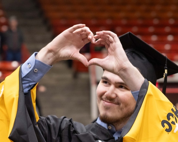 HCC Graduate holding up a heart with his hands at the commencement ceremony