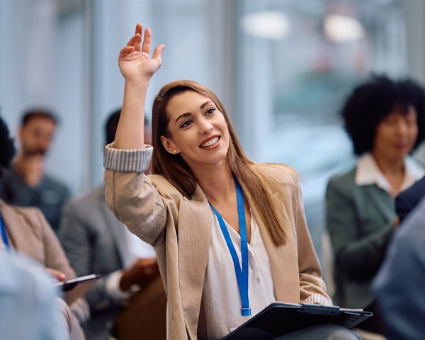A manager raising her hand to ask a. question during a training session.