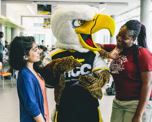 Two HCC students talk with school mascot Swoop.
