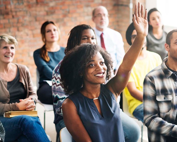 A woman raises her hand during a business seminar.
