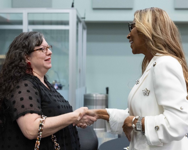 Two ladies shake hands during an HCC Alumni event.