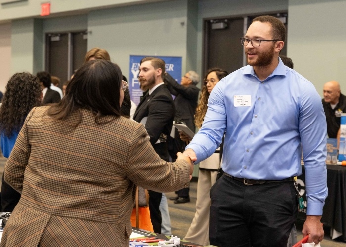 Student attending the HCC Engineering job fair meeting with and shaking a recruiters hand