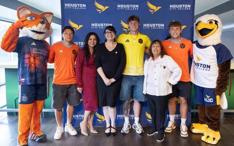 The Houston Dynamo mascot, members of the soccer team, HCC officials and the HCC mascot pose for a photo.