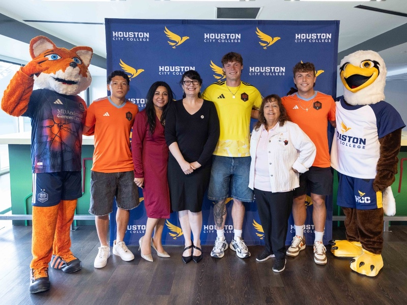 The Houston Dynamo mascot, members of the soccer team, HCC officials and the HCC mascot pose for a photo.