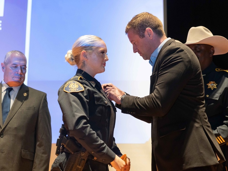 An HCC cadet receives her badge from a law enforcement agency.